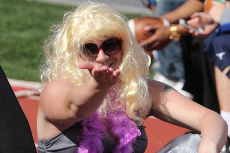 a woman wearing a wig and sunglasses blowing a kiss