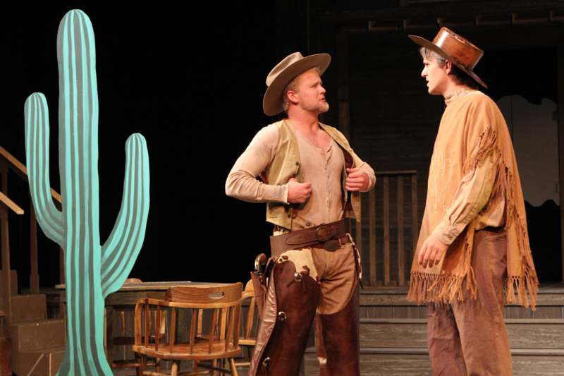 a man in cowboy clothes and cowboy boots talking to another man