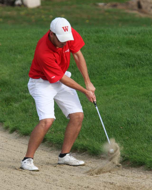 a man in a red shirt and white cap playing golf