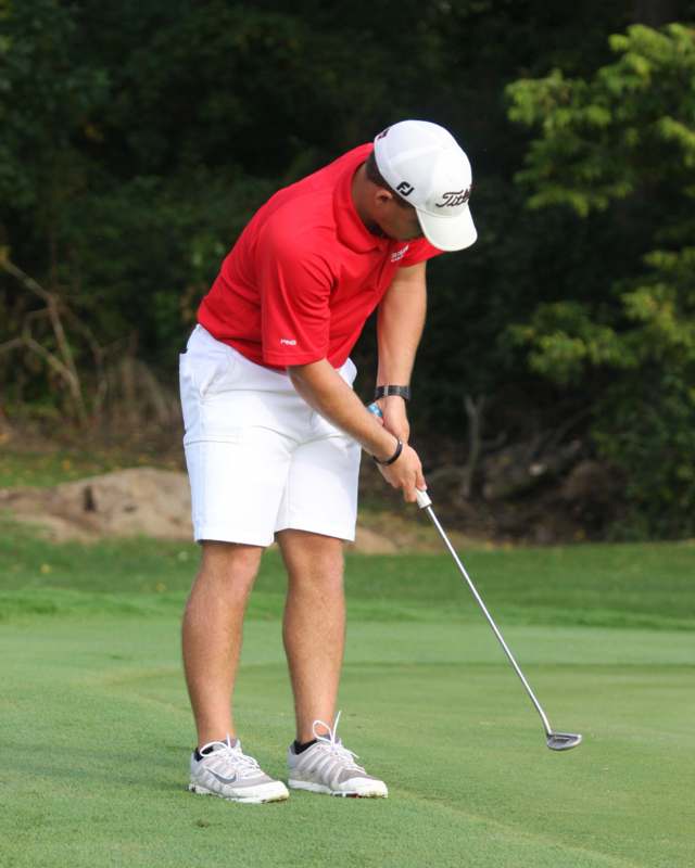 a man in a red shirt and white shorts holding a golf club