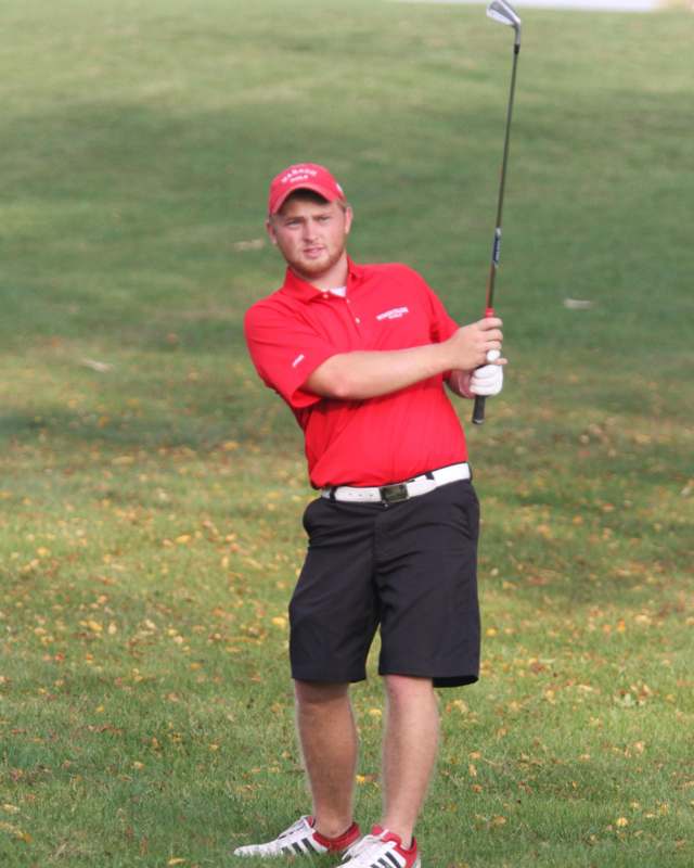 a man in a red shirt and black shorts holding a golf club