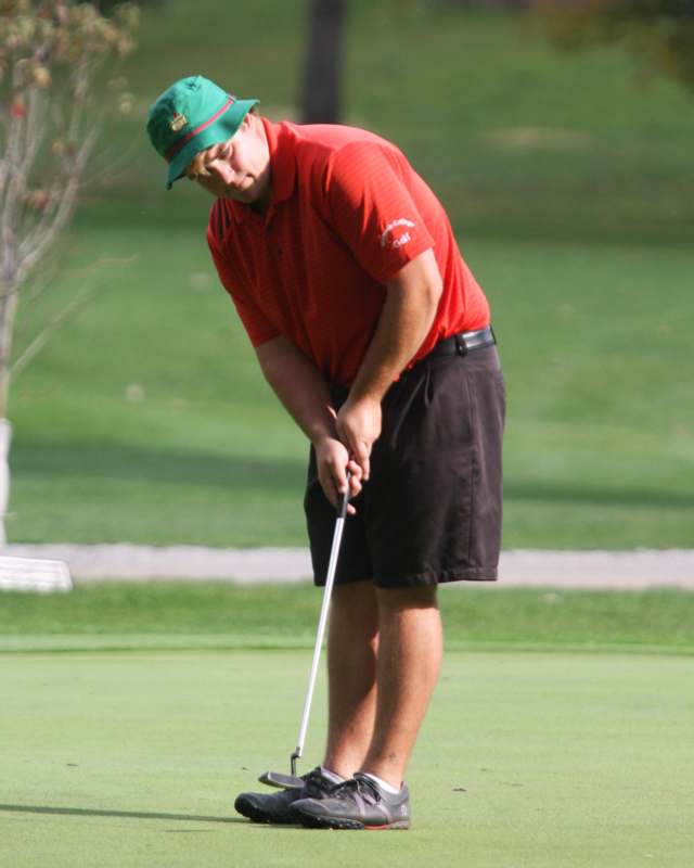 a man in a red shirt and green hat playing golf