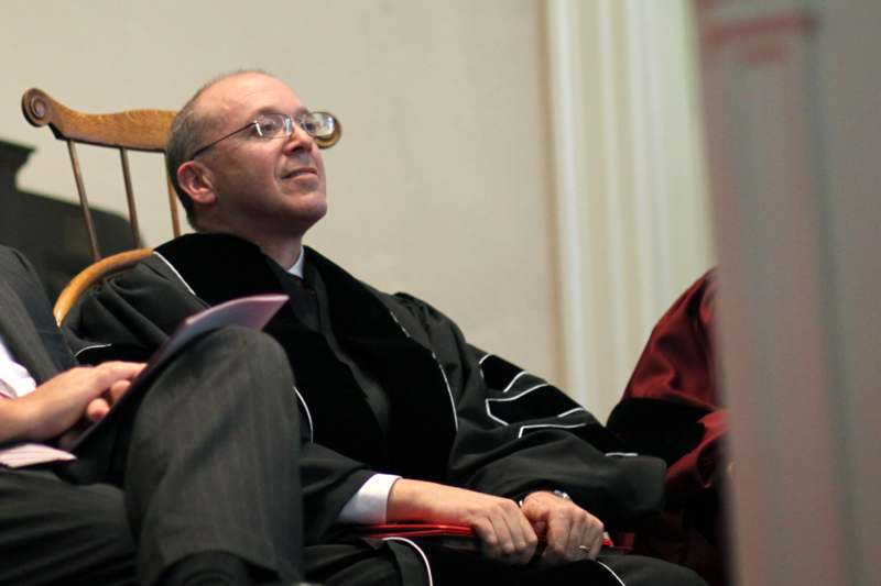 a man in a black robe sitting in a chair