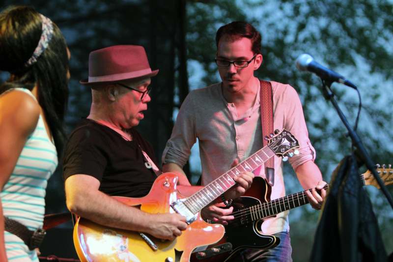 a man playing guitar with another man on stage