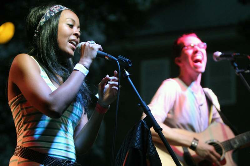a woman singing into a microphone with a man playing guitar