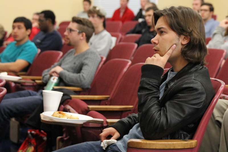 a man sitting in a lecture hall with a plate of food
