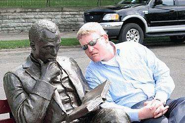 a man sitting next to a statue