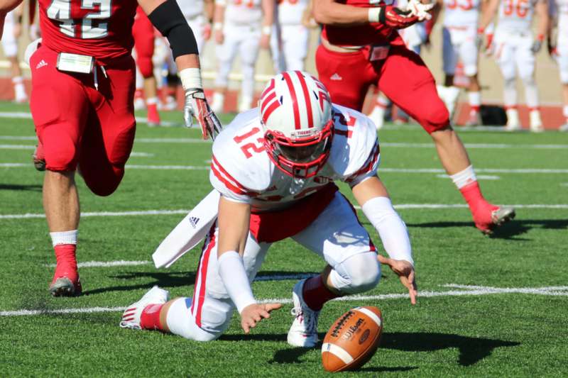 a football player in a red helmet on the ground with a ball