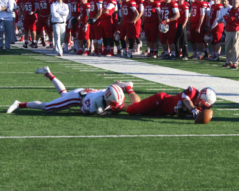 a football player falling down to catch a football
