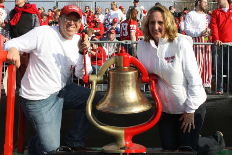 a man and woman posing for a picture with a bell