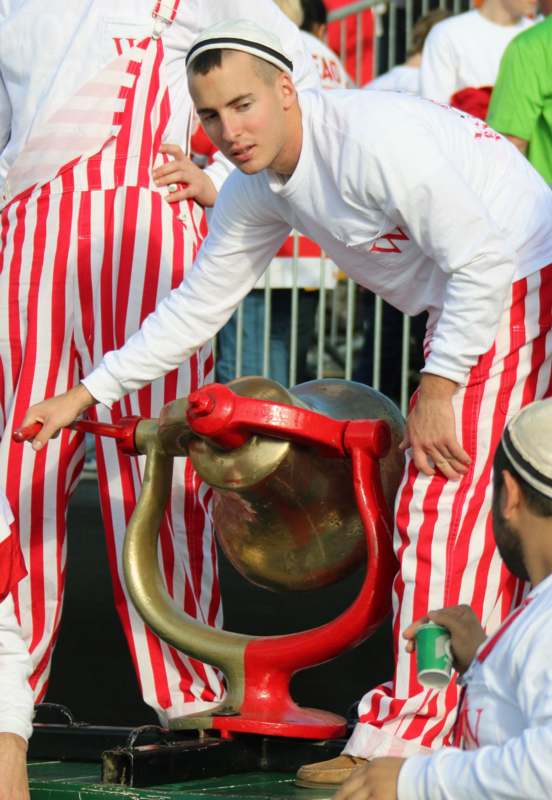 a man in red and white striped pants holding a large gold object