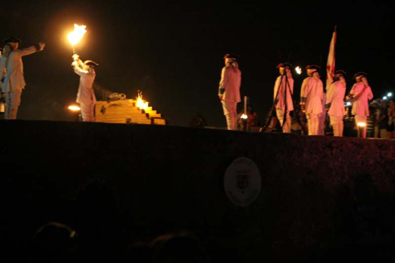 a group of people in white uniforms holding torches