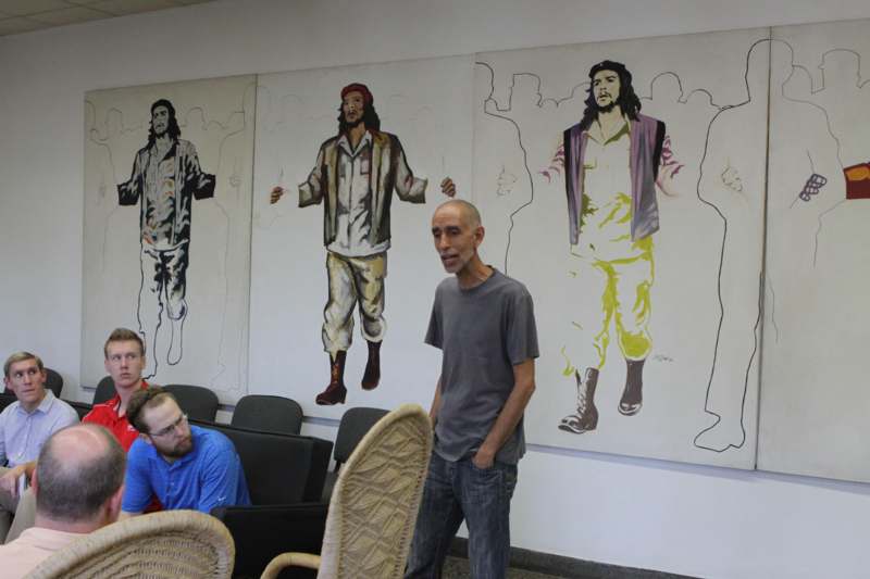 a man standing in front of a large mural of men