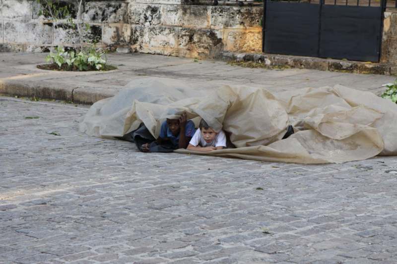 two boys under a tarp on a street