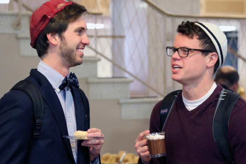 a couple of men talking and drinking coffee