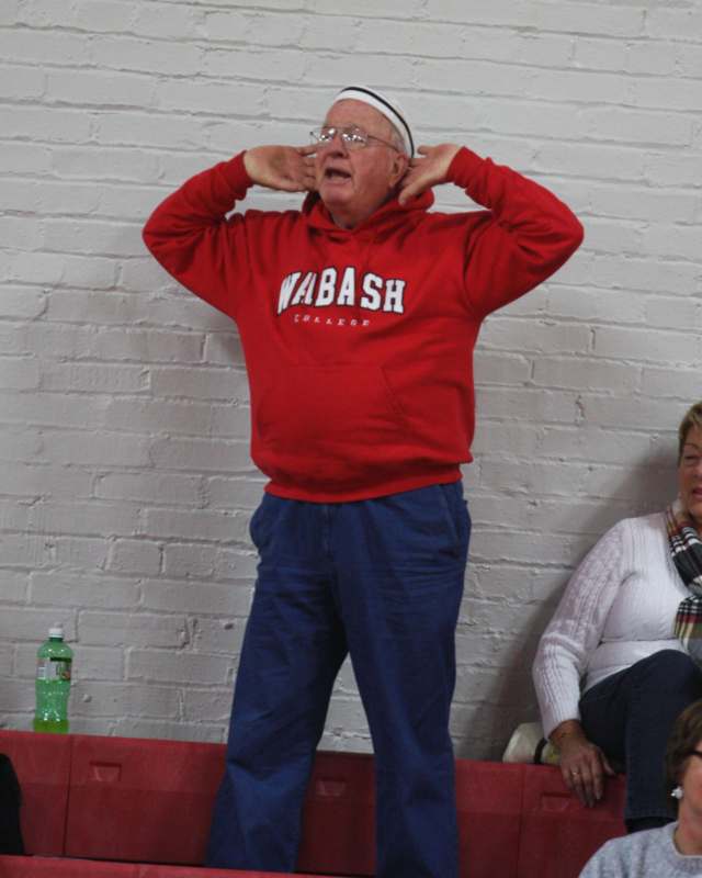 a man in a red hoodie with his hands on his ears