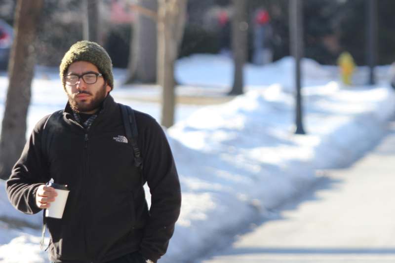 a man walking on a snowy sidewalk