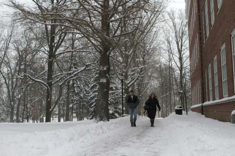 a man and woman walking on a snowy sidewalk