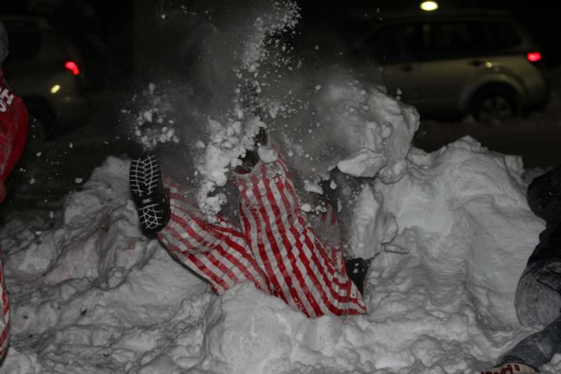 a person in a red and white striped jumpsuit buried in snow