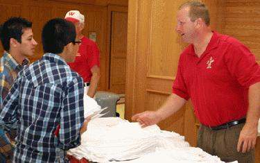 a man in red shirt standing next to a table full of white napkins