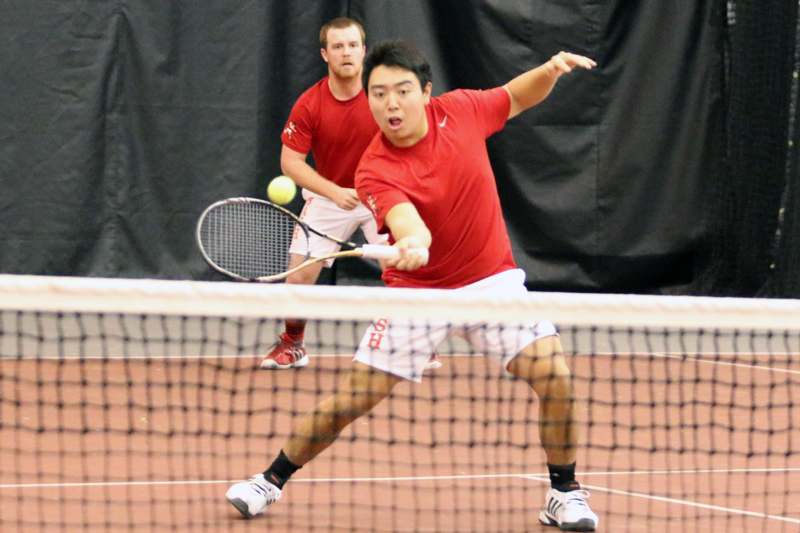 a man hitting a tennis ball with his racket