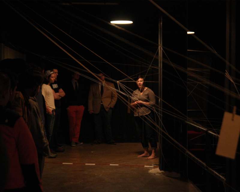 a person standing in a dark room with many strings