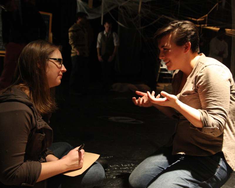 a woman sitting on the floor talking to another woman
