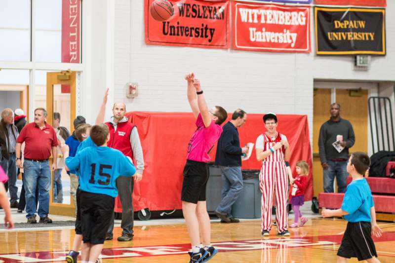 a man in a pink shirt jumping to shoot a basketball