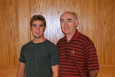 a man and a man standing in front of a wood wall