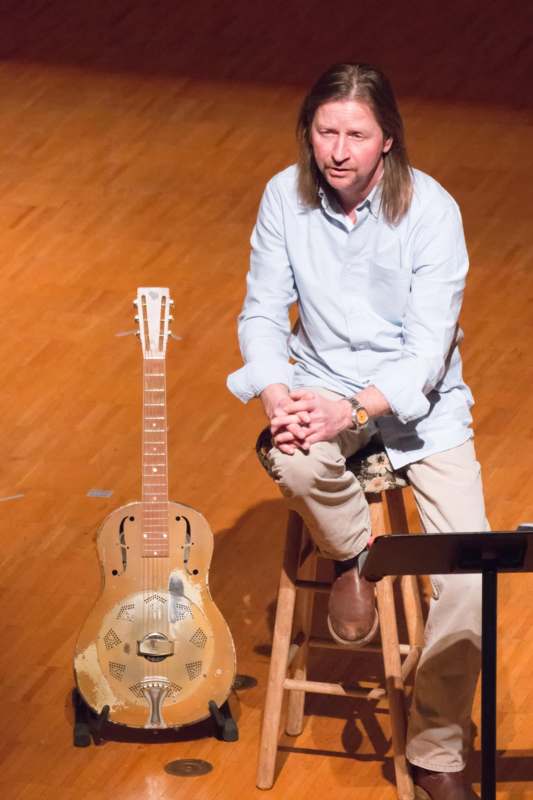 a man sitting on a stool with a guitar