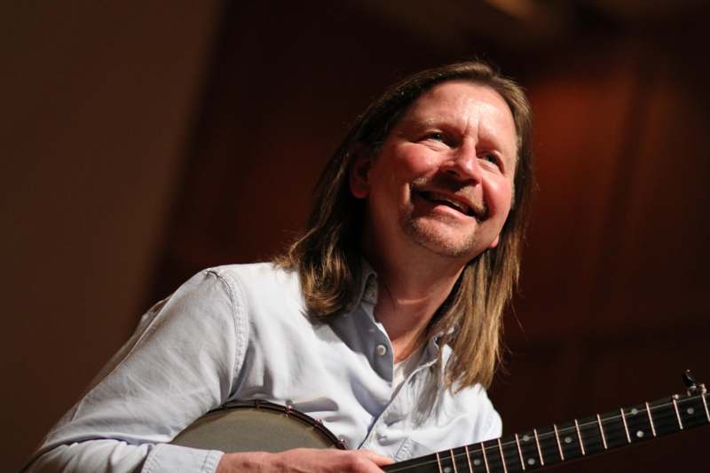 a man with long hair holding a banjo