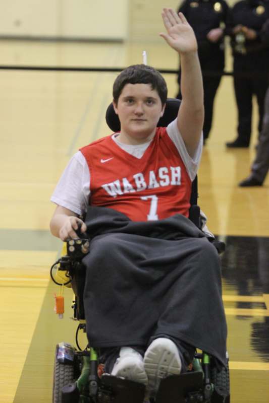 a boy in a wheelchair raising his hand