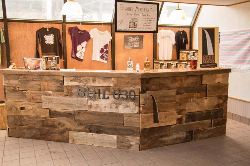 a wooden counter with a sign and t-shirts on the wall