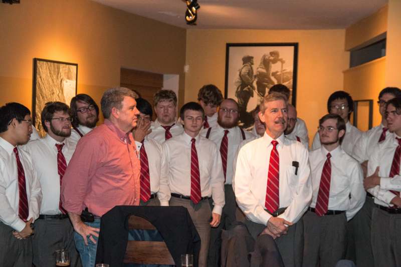a group of men in white shirts and red ties standing in a room