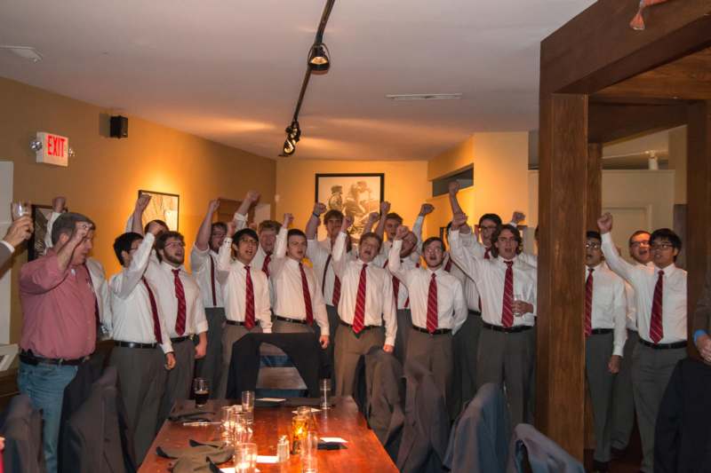 a group of men in white shirts and red ties