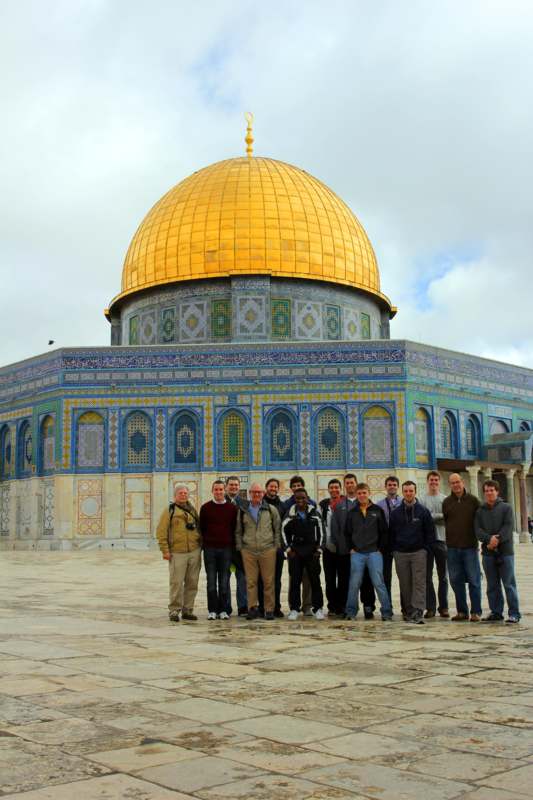 a group of people posing for a photo in front of Dome of the Rock