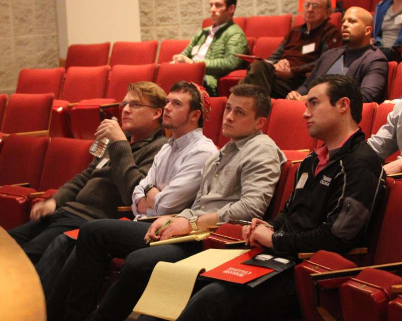 a group of men sitting in a red auditorium