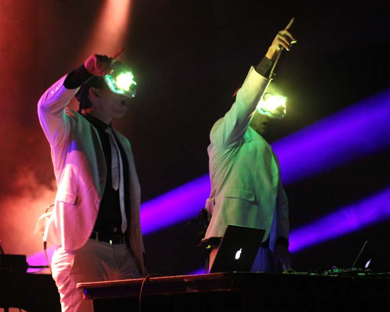 two men wearing white suits and holding their hands up