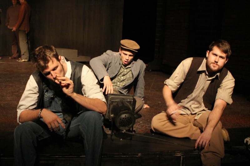 a group of men sitting on a stage smoking