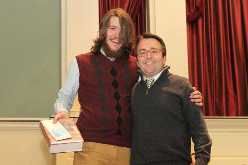 a man holding a book and smiling with a man in glasses