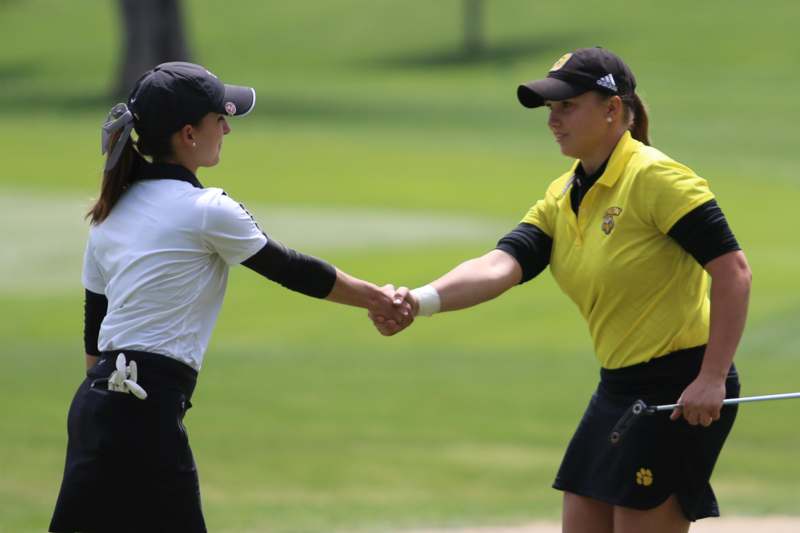 two women shaking hands on a golf course