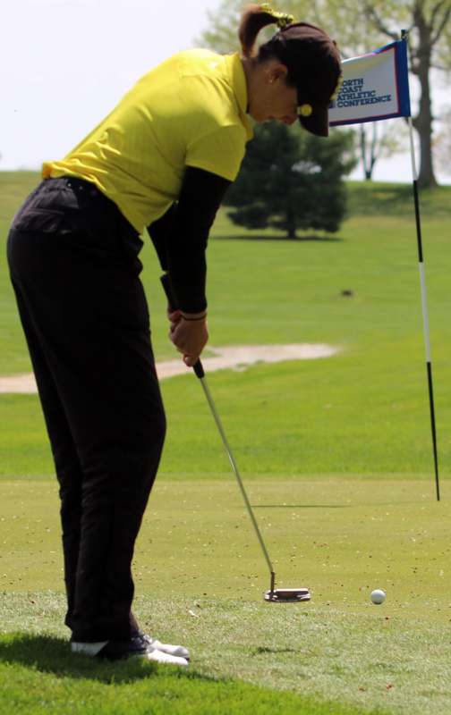 a person in a yellow shirt and black pants playing golf