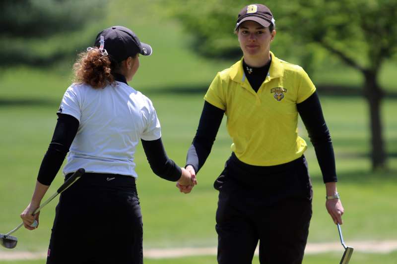 two women holding hands on a golf course