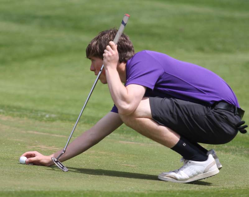 a man in purple shirt holding a golf club