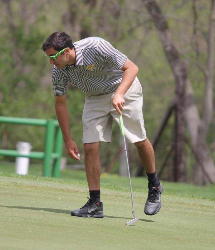 a man in a striped shirt and shorts holding a golf club