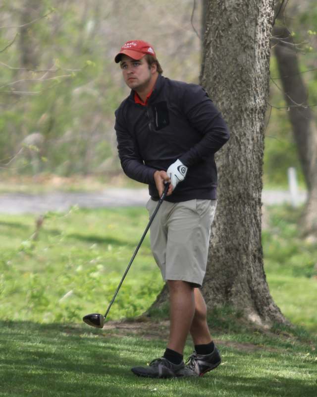 a man playing golf near a tree
