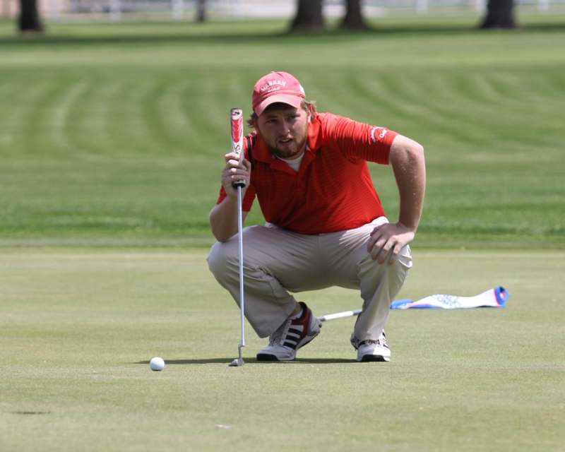 a man in a red shirt and cap holding a golf club