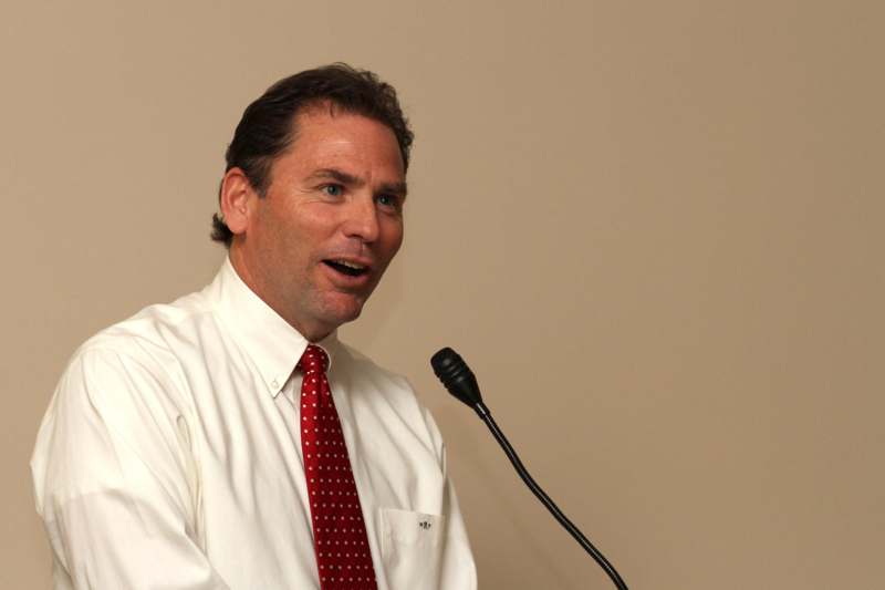 a man in a white shirt and red tie speaking into a microphone