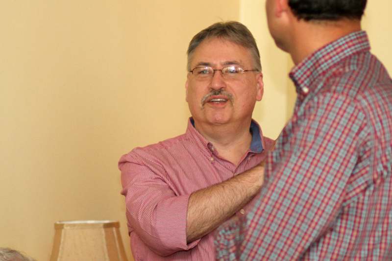 a man wearing glasses and a red shirt talking to another man