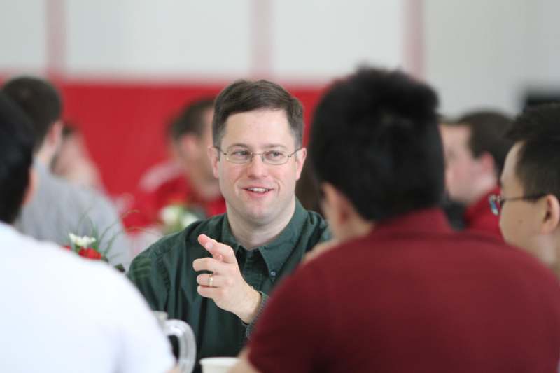 a man in a green shirt talking to a group of people